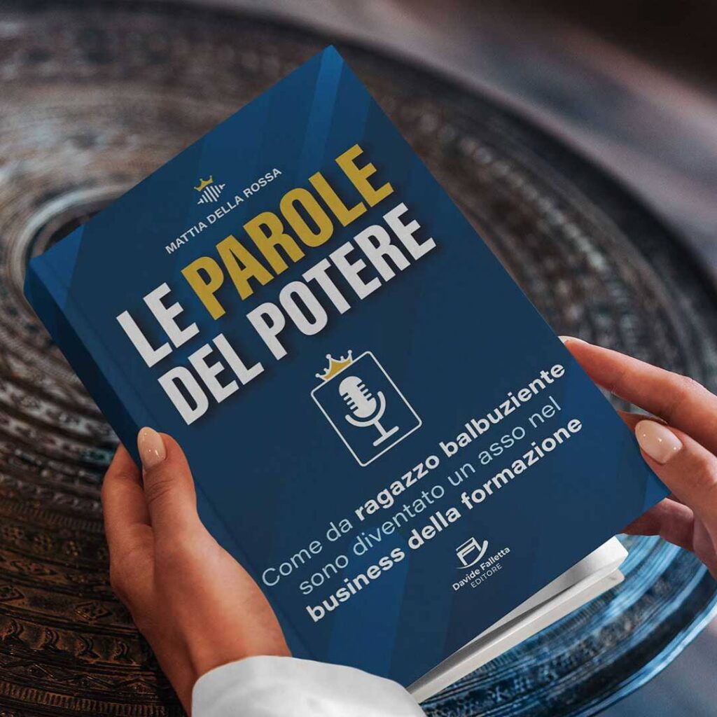 Mani femminili tengono il libro Le Parole del Potere con copertina blu, poggiato su un tavolino decorato